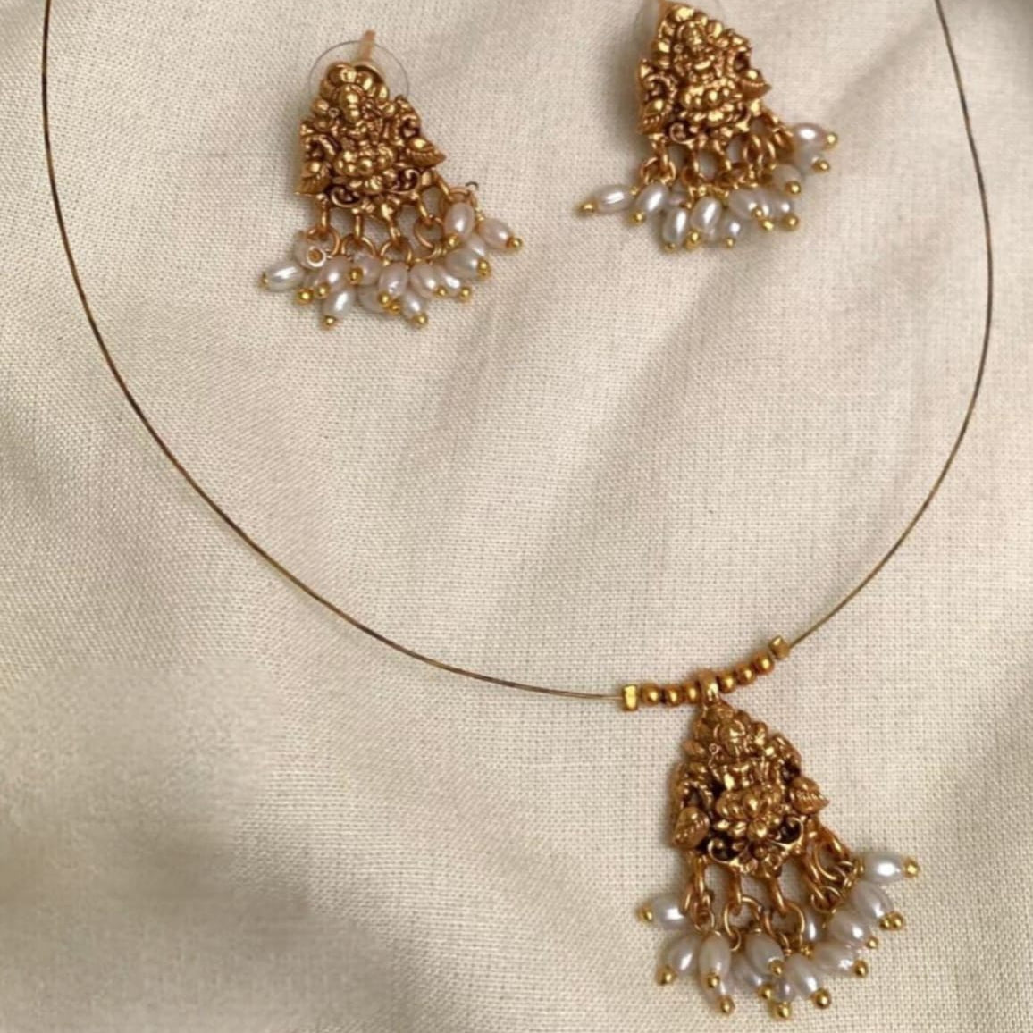 The Devika Set – Invisible Antique Gold Lakshmi Pendant with Pearl Drops: Antique Gold Matte Finish Lakshmi Pendant Set with Pearl Clusters | Minimalist Wire Choker & Matching Earrings
